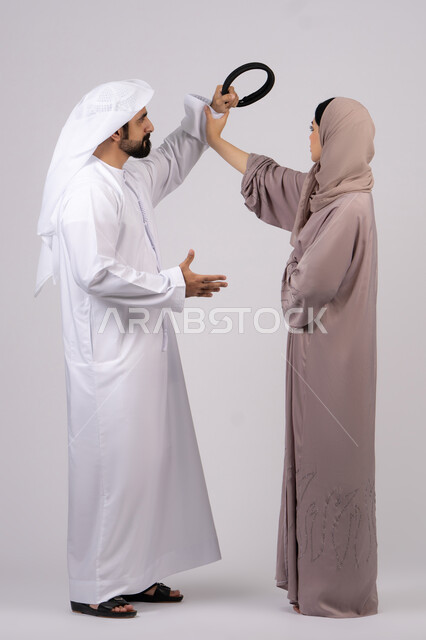 A quarrel between spouses, a woman defending herself, family problems and domestic conflict, a crisis in family relations, a portrait of an Arab Gulf Emirati couple arguing with each other, white background