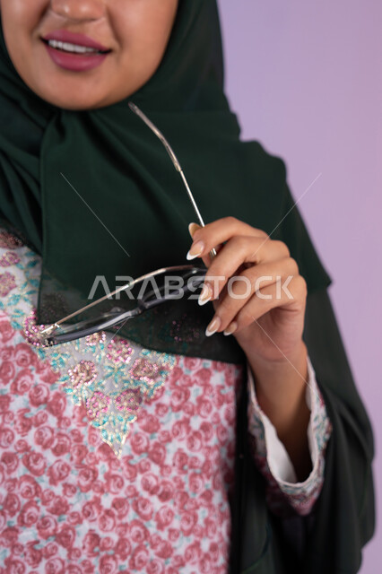 ملامح النعومة والانوثة، الاهتمام بالموضة والأناقة, بورترية مقرب لامراة عربية خليجية إماراتية ترتدي العباءة الملونه تمسك بيدها النظارة الشمسية , شابة سعودية تقف بإيماءات الدلع و الانوثه, خلفية ملونه