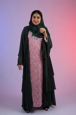 النعومة والشياكة والأنوثة، مفهوم العناية بالجمال والإطلالة المتميزة، بورترية لسيدة عربية خليجية اماراتية مبتسمه محجبة ترتدي العباءه الملونه تمسك بيدها النظارة الشمسية ، سيدة سعودية تنظر الى الكاميرا بايماءات السعادة و السرور، الجسم بالطول الكامل،  خلفية ملونه