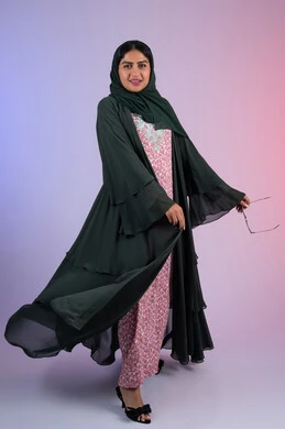The concept of elegance and chic, modern and elegant veiled clothing, portrait of an Emirati Gulf Arab woman wearing a veil and an abaya, holding sunglasses in her hands, standing straight with an expression of self-confidence, a Saudi woman looking with gestures of cheerfulness and admiration, full-length body, colored background