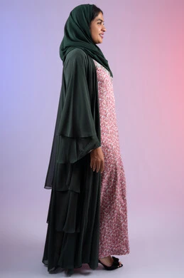 الجمال والاهتمام بالمظهر الخارجي، سيدة سعودية تنظر  بإيماءات السرور والسعادة، مفهوم الأنوثة والنعومة، بورتريه  من الجانب لامرأة عربية خليجية اماراتية ترتدي الحجاب والعباءة تقف باستقامة بتعابير الثقة بالنفس، الجسم بالطول الكامل، خلفية ملونه