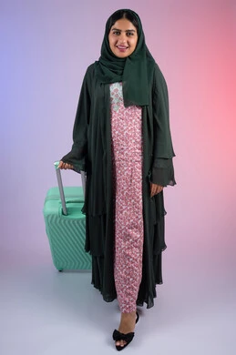 Fun summer trip, feeling happy and joyful, a young Saudi woman preparing for a fun summer trip, a portrait of a veiled young Gulf Arab Omani woman wearing an abaya holding a suitcase with enthusiastic gestures, a full-length body image, a colorful background