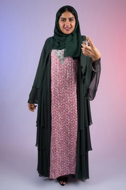 الشغف برش العطورات, التسويق لمنتجات العطور ، سيدة اماراتية تستخدم المستحضرات النسائية, بورترية لامرأة عربيه سعودية خليجية محجبة مبتسمة تمسك بيدها زجاجة وتقوم برش العطر، الجسم بالطول الكامل، خلفية ملونة