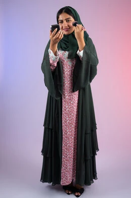 صالون نسائي راقي، التسويق لمنتجات التجميل ، مفهوم الانوثه والاهتمام بالمظهر الخارجي، مكياج وميكاب تتوريال، بورترية لفتاه عربيه سعودية خليجيه ترتدي العباءة والحجاب تحمل بيدها فرشاة توريد الخدود ، سيدة اماراتية تستخدم أدوات تجميل نسائيه عصريه،الجسم بالطول الكامل، خلفية ملونه