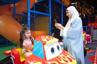 توثيق اللحظات السعيدة، تحسين جودة الحياة باستخدام التقنية الحديثة، سيدة عربية خليجية اماراتية ترتدي العباءه الملونه تقضي وقتها مع ابنتها ،مشاركة الاطفال بالانشطة الترفيهية ، انشطة صيفية ترفيهية ، اللعب بالالعاب الترفيهية، قضاء وقت عائلي ممتع، عطلة صيفية سعيدة، ام سعودية تقوم بالتقاط صورة تذكارية عبر الهاتف المحمول