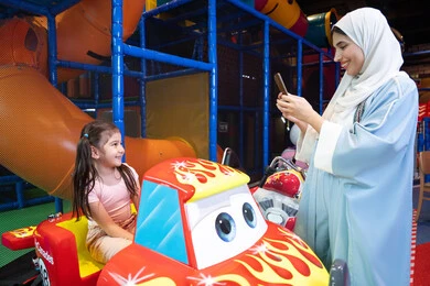 تحسين جودة الحياة باستخدام التقنية الحديثة ، توثيق اللحظات السعيدة، سيدة عربية خليجية اماراتية ترتدي العباءه الملونه تقضي وقتها مع ابنتها ،مشاركة الاطفال بالانشطة الترفيهية ، انشطة صيفية ترفيهية ، اللعب بالالعاب الترفيهية، قضاء وقت عائلي ممتع، عطلة صيفية سعيدة، ام سعودية تقوم بالتقاط صورة تذكارية عبر الهاتف المحمول