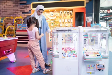 فتاة صغيرة عربية خليجية ترتدي الزي الكاجوال تلهو وتلعب بحماس ونشاط، تفريغ الطاقة باللعب واللهو والمرح، ارتياد الصالة المغلقة المخصصة للأطفال، القيام بنشاط ترفيهي في عطلة نهاية الأسبوع، ام عربية خليجيه اماراتية ترتدي العباءة الملونه تقوم بالتنزه مع ابنتها