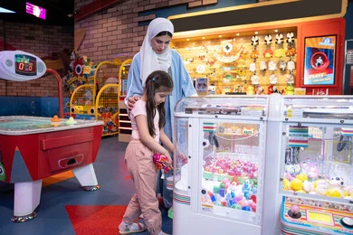 ارتياد الصالة المغلقة المخصصة للأطفال، القيام بنشاط ترفيهي في عطلة نهاية الأسبوع، فتاة صغيرة عربية خليجية ترتدي الزي الكاجوال تلهو وتلعب بحماس ونشاط، تفريغ الطاقة باللعب واللهو والمرح ، ام عربية خليجيه اماراتية ترتدي العباءة الملونه تقوم بالتنزه مع ابنتها