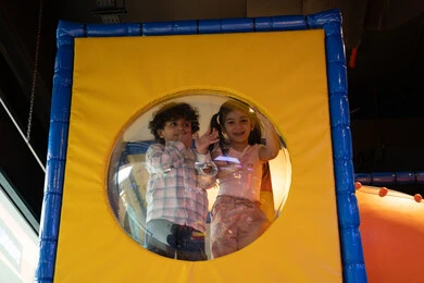 Feelings of fun and joy, fun entertainment centers in the UAE, having fun in the fun land, two Emirati Gulf Arab children wearing casual clothes enjoying playing in the amusement park, entertainment and recreation, recreational activities