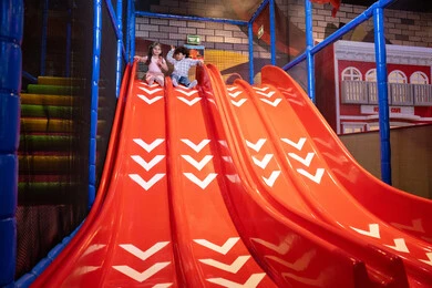 Playing with recreational games, sliding on the slide, gestures of fun and happiness, two Emirati Gulf Arab children wearing casual clothes enjoying playing on the slide, exploiting free time in entertainment and play
