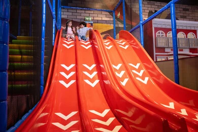 الاستمتاع في مركز الالعاب الترفيهية، التزحلق على الزحليقه, ايماءات المرح و السرور, طفلان عربيان خليجيان اماراتيان يرتديان الزي الكاجوال يستمتعان باللعب على لعبة التزحلق، استغلال وقت الفراغ في التسلية واللعب