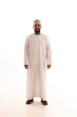 The concept of elegance and masculinity, standing upright and looking with gestures of self-confidence, taking care of the external appearance, a portrait of a young Arab Gulf Omani man wearing a dishdasha and kumma with expressions of cheerfulness and joy, full body length, white background.