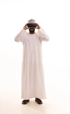 مشاهدة المشاهد الخيالية، استخدام الأجهزة التقنية الحديثة، التفاعل والاندماج مع الواقع الافتراضي، بورتريه لشاب عربي خليجي عماني يرتدي الدشداشة والكمه يضع نظارات الفي آر، قضاء أوقات الفراغ بشكل ممتع، الجسم بالطول الكامل، خلفية بيضاء