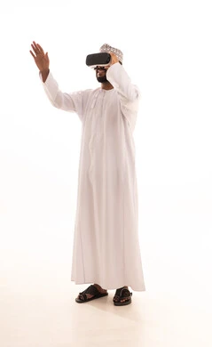 استخدام الأجهزة التقنية الحديثة، التفاعل والاندماج مع الواقع الافتراضي، رؤية المشاهد الخيالية،بورتريه لشاب عربي خليجي عماني يرتدي الدشداشة والكمه يضع نظارات الفي آر، قضاء أوقات الفراغ بشكل ممتع، الجسم بالطول الكامل، خلفية بيضاء