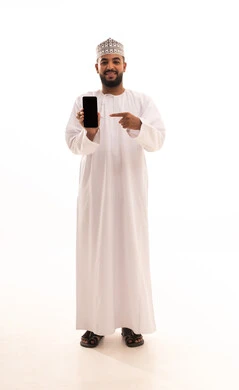 A blank black screen displayed on a mobile phone, looking at the camera with gestures of happiness and joy, using modern technological means, a portrait of a young Arab Gulf Omani man wearing a dishdasha and kumma holding the mobile phone and pointing at it with his index finger, a full-body image, white background.