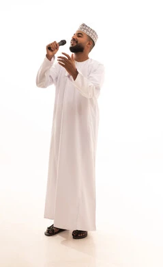 Musical theatrical art, artistic talents in the world of music, presenting theatrical performances, practicing the hobby of singing for fun and entertainment, a portrait of a smiling young Arab Gulf Omani man wearing a dishdasha and kumma holding a microphone in his hand, full body length, white background.