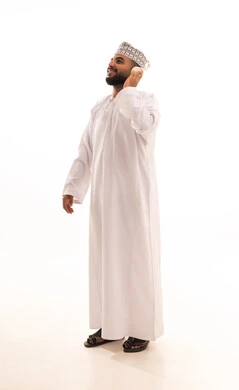 إيماءات السعادة و الاندماج مع الأغنية، مواهب غنائية فنية، بورتريه لشاب عربي خليجي عماني مبتسم يرتدي الدشداشة و الكمة يضع الهيدفون، الاستماع إلى الموسيقى, تسجيل مقطع صوتي غنائي، صورة الجسم بالكامل، خلفيه بيضاء