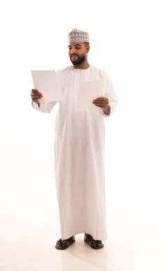 Preparation of work-related reports, reviewing and following up on office plans and projects, a portrait of a young Arab Gulf Omani man wearing a dishdasha and kumma holding a set of white papers in his hand, checking the reading of notes, full-body image, white background.