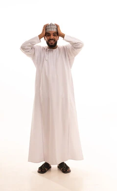 الانبهار بشيء مفاجئ، الشعور بالدهشة والصدمة والذهول, بورتريه لشاب عربي خليجي عماني يرتدي الدشداشة و الكمه ينظر الى الكاميرا يضع يديه على رأسه بإيماءات التعجب والانبهار, صورة الجسم بالطول الكامل, خلفية بيضاء