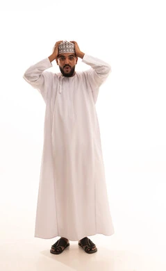The feeling of astonishment, shock, and amazement, being surprised by something, a portrait of a young Arab Gulf Omani man wearing a dishdasha and kumma looking at the camera with his hands on his head in gestures of wonder and amazement, full-body image, white background.
