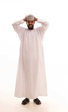 التفاجؤ من شيء ما، الشعور بالدهشة والصدمة والذهول, بورتريه لشاب عربي خليجي عماني يرتدي الدشداشة و الكمه ينظر الى الكاميرا يضع يديه على رأسه بإيماءات التعجب والانبهار, صورة الجسم بالطول الكامل, خلفية بيضاء
