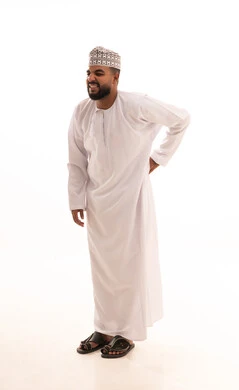 آلام الظهر والعمود الفقري والتهاب المفاصل، بورتريه لشاب عربي خليجي عماني يرتدي الدشداشة والكمه يقف بصعوبة ويمسك ظهره بيديه بإيماءات المعاناة، الإحساس بالألم والإصابة بمرض الديسك، صورة الجسم بالطول الكامل، خلفية بيضاء