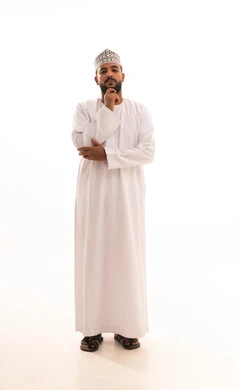 التركيز وشرود الذهن والتمعن ،التأمل والتخطيط للمستقبل، إيجاد حل لمشكلة ما، بورتريه لرجل عربي عماني يرتدي الدشداشة والكمه يضع يده على ذقنه و ينظر إلى شيء ما بإيماءات التفكير، صورة الجسم بالطول الكامل، خلفية بيضاء