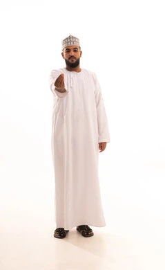 مفهوم الصبر والتريث و التأني, التهديد و التوعد لشيء ما، بورتريه لشاب عربي خليجي عماني يرتدي الدشداشة و الكمة ينظر الى الكاميرا ويرفع يده نحو الأعلى بإيماءات طلب الإنتظار, إمهال بعض الوقت لفعل شيء، صورة الجسم بالطول الكامل, خلفية بيضاء