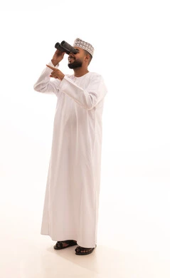 Seeing distant things through a telescope, a love for adventure and exploration, a portrait of a young Arab Gulf Omani man wearing a dishdasha and kumma looking through a binocular (telescope) pointing with his index finger at something with gestures of joy and happiness, full-body image, white background.