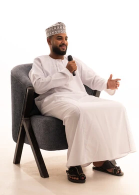 Recording a singing audio clip, enjoying the performance of vocal talents, presenting theatrical shows, a portrait of an Arab Omani Gulf man wearing a dishdasha and a kumma holding a microphone in his hand, white background.