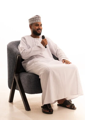 Enjoying the performance of vocal talents, presenting theatrical shows, a portrait of an Arab Omani Gulf man wearing a dishdasha and kumma holding a microphone, recording a vocal music clip, white background.
