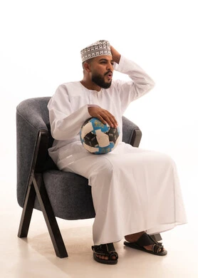 مفهوم الاستياء لعدم فوز الفريق المفضل، قضاء وقت ممتع بمتابعة المباراة، بورتريه لرجل عربي عماني يرتدي الدشداشة والكمه يجلس على كرسي يضع يديه على رأسه بإيماءات الحزن والخسارة، المباريات والألعاب الرياضية، خلفية بيضاء