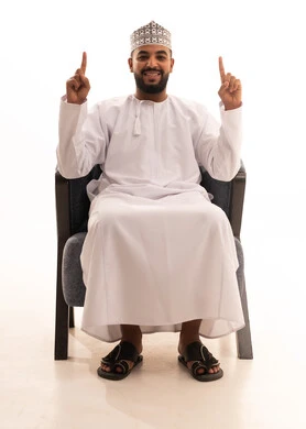 تحديد موقع معين، الإشارة والتوضيح إلى شيء ما، بورتريه لرجل عربي عماني يرتدي الدشداشة والكمه يجلس على كرسي يشير بإصبعيه السبابة للاعلى بتعابير هذا المكان هنا, خلفية بيضاء تحديد موقع معين، الإشارة والتوضيح إلى شيء ما، بورتريه لرجل عربي عماني يرتدي الدشداشة والكمه يجلس على كرسي يشير بإصبعيه السبابة للاعلى بتعابير هذا المكان هنا, خلفية بيضاء