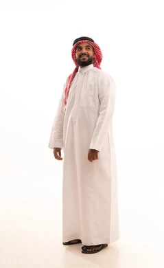 الاهتمام بالأناقة والمظهر الخارجي ،مفهوم الرجولة والقوة والثقة بالنفس، بورتريه لرجل عربي خليجي سعودي يرتدي الشماغ والزي التقليدي ينظر الى  شيء ما بإيماءات السرور والسعادة ، الجسم بالطول الكامل، خلفية بيضاء