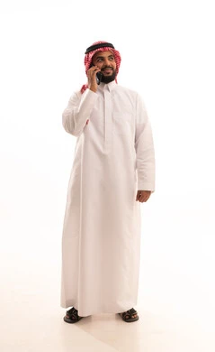 The use of modern devices and technologies, a portrait of an Arab Saudi Gulf man wearing a ghutrah and traditional thobe holding a mobile phone, making phone calls, chatting, and communicating with friends with gestures of happiness and joy, full-body image, white background.