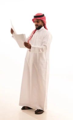التدقيق في قراءة الملاحظات، تعابير الفتكير والتركيز، اعداد التقارير الخاصة بالعمل، بورتريه لرجل عربي خليجي سعودي يرتدي الشماغ والثوب التقليدي يحمل بيده مجموعة من الوثائق والاوراق البيضاء، مراجعة ومتابعة الخطط والمشاريع ، صورة الجسم بالكامل، خلفية بيضاء