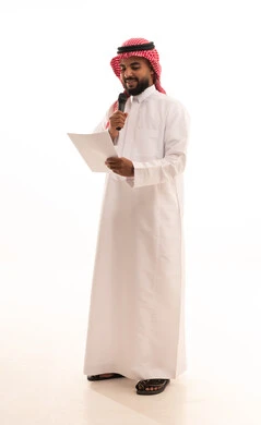 العمل في تقديم الفقرات والبرامج الفنية الترفيهية، تبادل الحوار والاستفادة من الخبرات، إلقاء المحاضرات وإقامة الندوات، بورتريه لرجل عربي خليجي سعودي يرتدي الشماغ والثوب التقليدي يحمل بيده المايكروفون و مجموعه من الاوراق، الجسم بالطول الكامل، خلفية بيضاء