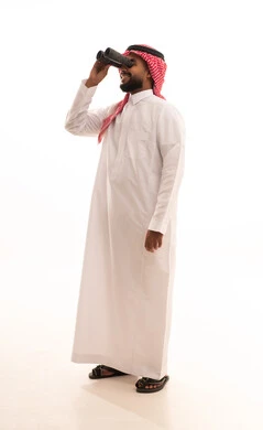Searching for something and expanding the field of vision using binoculars, the concept of exploration and adventure, future visions among youth, a portrait of an Arab Gulf Saudi man wearing a ghutrah and traditional thobe looking through binoculars, full body length, white background.