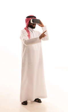 Immersion and simulation of the imaginary world, referring to something, enjoyment and entertainment through viewing via virtual reality glasses, a portrait of a Saudi Arabian Gulf man wearing a ghutrah and traditional thobe, wearing 3D glasses (VR), technological and technical development, full-body, white background.