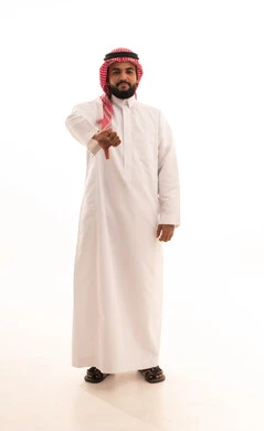 الشعور بالانزعاج من شيء ما، حركات يدين تدل على الرفض وعدم القبول والفشل، بورتريه لرجل عربي خليجي سعودي يرتدي الشماغ والثوب التقليدي يشير بإصبعه الابهام الى الأسفل بإيماءات عدم الاعجاب والتقييم السلبي، صورة الجسم بالطول الكامل, خلفية بيضاء