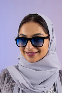 Enjoying owning modern accessories, caring about elegance and appearance, Emirati woman wearing abaya and glasses, gestures of femininity and beauty, close-up portrait of a veiled Saudi Arabian Gulf woman trying on new sunglasses, looking at the camera with an expression of pleasure, colorful background