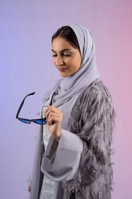 Fashion show and modern models, buying modern women's accessories, the concept of femininity, elegance and beauty, an Emirati woman wearing an abaya and colored glasses, a portrait of a veiled Saudi Arabian Gulf woman holding sunglasses, colored background