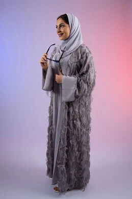 الاستمتاع بامتلاك اكسسوارات عصرية، الوقوف بتعابير الأنوثة والسرور, مفهوم الأناقة والجمال, الاهتمام بالمظهر الخارجي، سيدة اماراتية مبتسمة ترتدي عباءة، بورتريه لامرأة عربية خليجية سعودية محجبة تضع نظارات شمسية, الجسم بالطول الكامل، خلفية ملونة