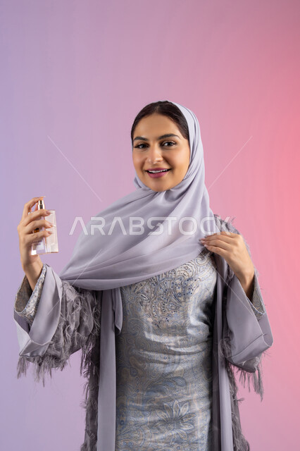 The concept of perfuming and fragrance, the use of fragrant oud, marketing of international perfumes and natural oils, Arab Gulf perfumes, an Emirati woman shopping for aromatic products, a portrait of a veiled Saudi Arab woman wearing an abaya spraying perfume, a colored background