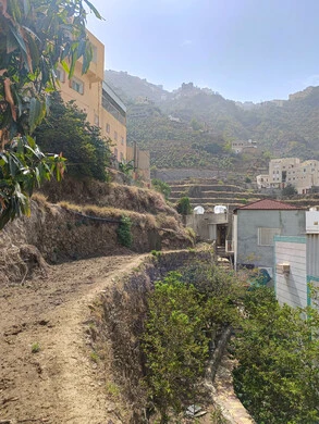  مكان ومنطقة سياحية طبيعية، الأشجار والنباتات ومساحات الطبيعة الخضراء، المدرجات الزراعية على السفوح الجبلية، البيوت القديمة الشعبية على جبال فيفاء في جازان جنوب المملكة العربية السعودية، القمم والمرتفعات الصخرية في النهار