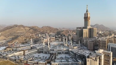 A sacred religious site and landmark in the Kingdom of Saudi Arabia, an aerial view of the architectural art of towers and skyscrapers in Mecca, a destination for Muslims from different countries, the progress and urban growth of hotels and buildings overlooking the Grand Mosque