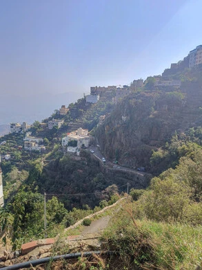 البيوت القديمة الشعبية على جبال فيفاء في جازان جنوب المملكة العربية السعودية، القمم والمرتفعات الصخرية في النهار، مكان ومنطقة سياحية طبيعية، الأشجار والنباتات ومساحات الطبيعة الخضراء، المدرجات الزراعية على السفوح الجبلية