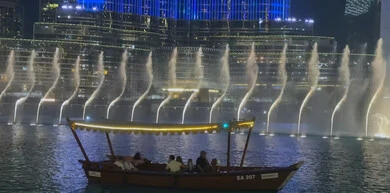 Entertainment activities and events, spending a fun time on the weekend, the famous Dubai Fountain illuminated in different colors at night, famous tourist places and landmarks in the United Arab Emirates