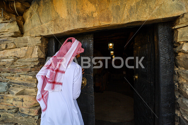  الفن الهندسي المعماري على الطراز القديم للمتاحف،  الحصون والقلاع التاريخية, المباني والمنشآت الحجرية المشيدة, المعالم والأماكن التراثية الثقافية المشهورة, صورة من الخلف لرجل عربي خليجي سعودي يرتدي الشماغ والثوب التقليدي يتجول في متحف اللد التراثي في منطقه الباحه
