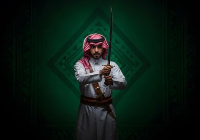 مفهوم الحرب والدفاع عن الوطن، إحياء ذكرى اليوم الوطني السعودي, التباهي بالأسلحة التقليدية السعودية, حب وشغف امتلاك السيوف التراثية, رجل عربي خليجي سعودي يرتدي الثوب التقليدي والشماغ يحمل بيده السيف